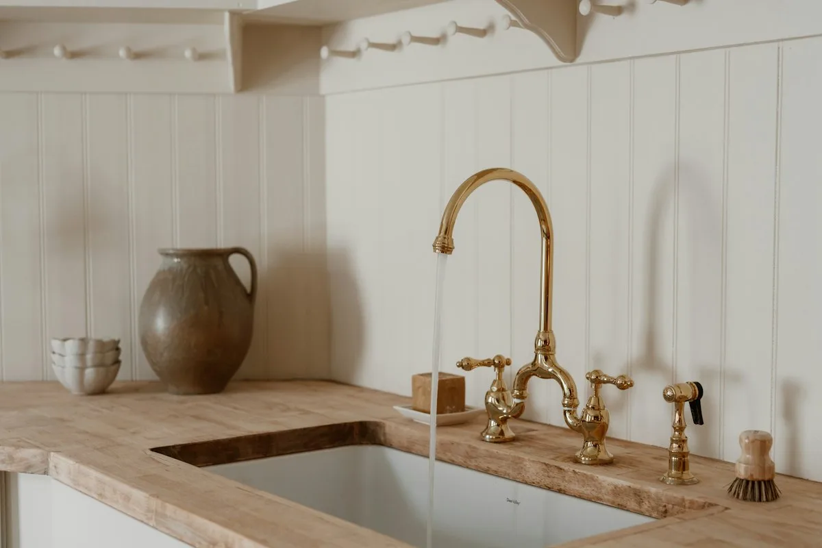 A brass tap with water running into a sink